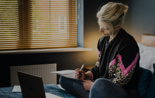 woman working on her laptop while sitting on her bed. When Do You Know Your First Draft Is Done