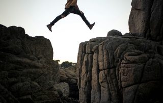person jumping from one rock to another